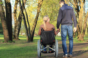Bildinhalt: eine junge Frau im Rollstuhl und ein junger Mann beim Spaziergang