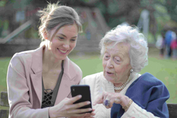 Bildinhalt: eine junge Frau erklärt einer älteren Frau ein Smartphone